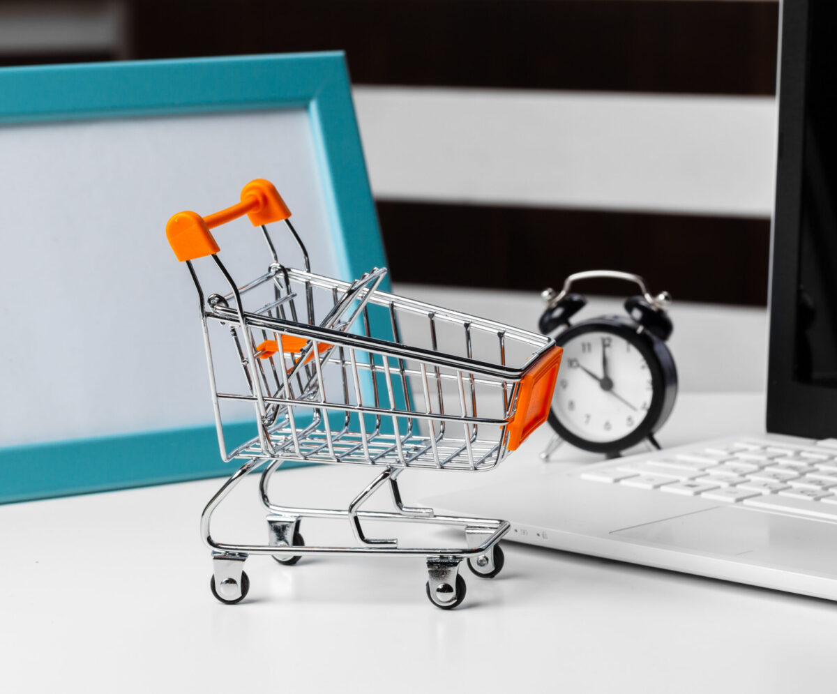 shopping online concept. small toy trolley and gadgets on the table. creative photo.